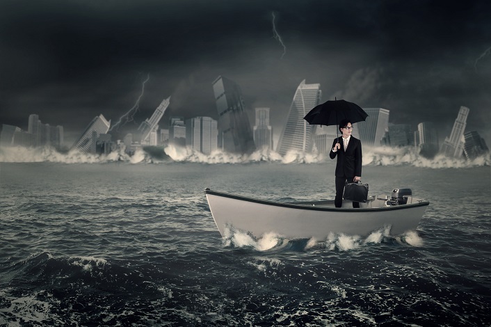 Young businessman standing on the boat while holding an umbrella and briefcase with a sinking town at the sea